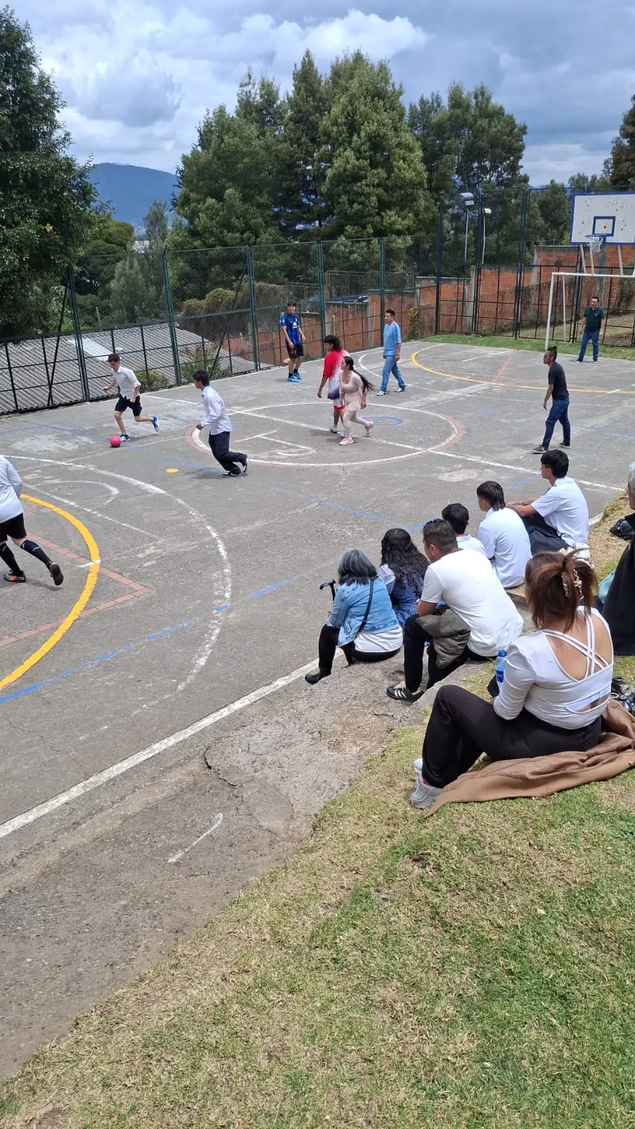 Estudiantes reunidos en la cancha de baloncesto durante una actividad deportiva
