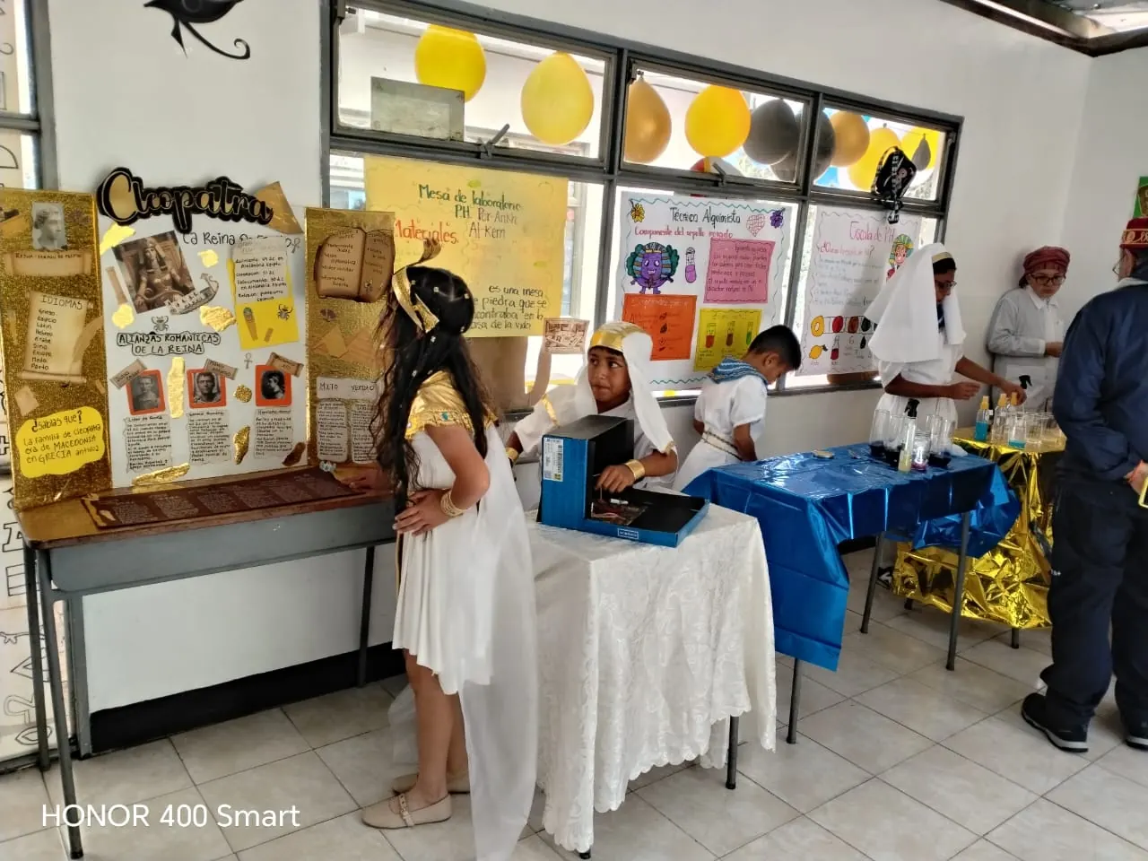 Estudiantes presentando un proyecto sobre Egipto en el aula, con carteles y vestuario