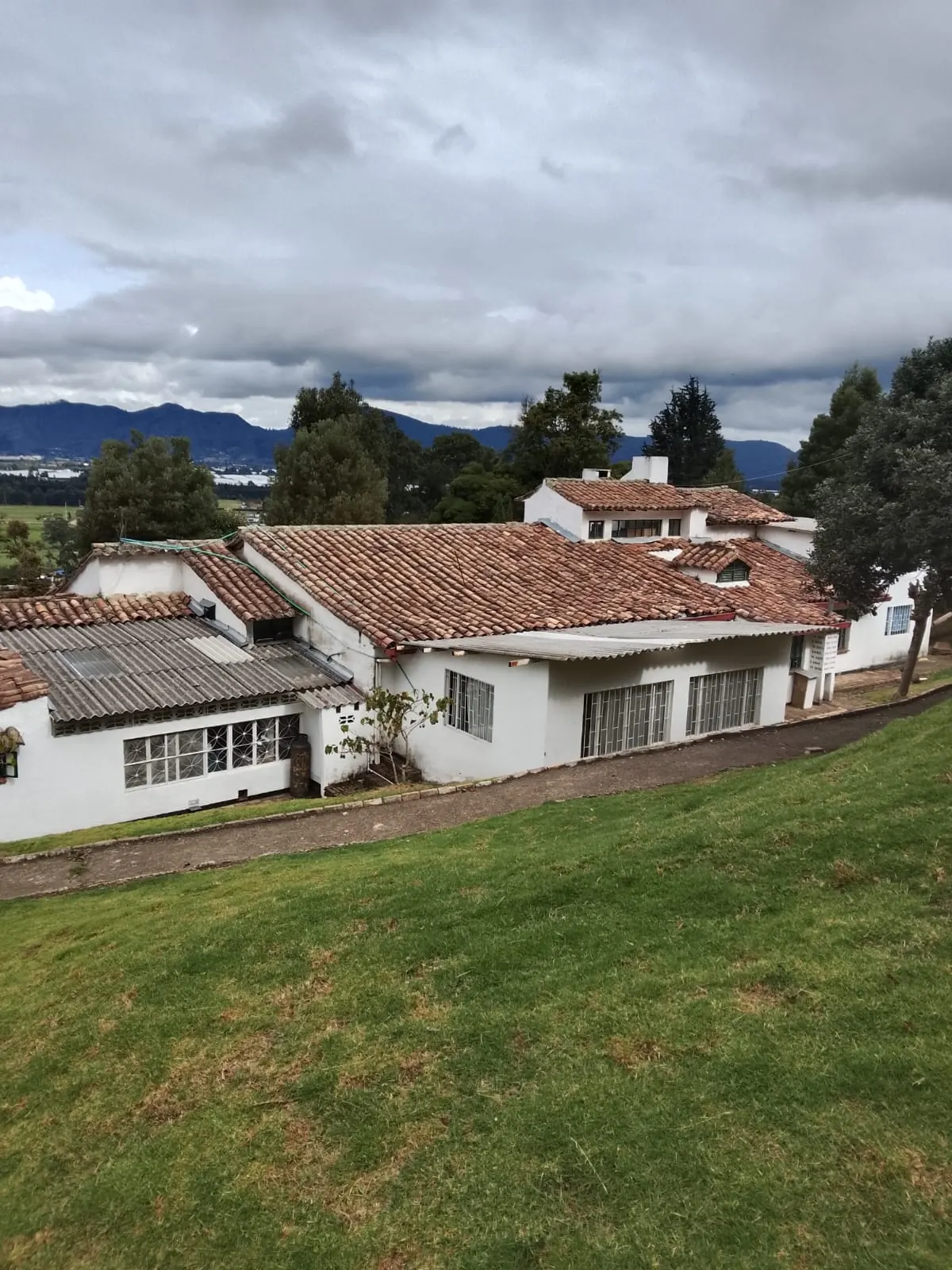 Zona verde del colegio con viviendas de teja roja al fondo